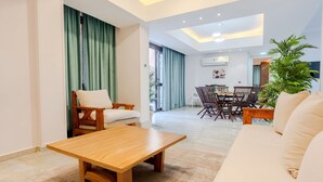 A modern living room with a wooden coffee table, a beige sofa, and a dining area with a wooden table and chairs. - Vesta - Luxury APT - 2BR - Sheikh Zayed I (Sheikh Zayed City)