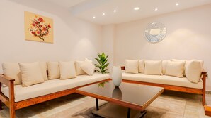A modern living room with two beige sofas, a wooden coffee table, a vase with a plant, and artwork on the walls. - Vesta - Luxury APT - 2BR - Sheikh Zayed I (Sheikh Zayed City)