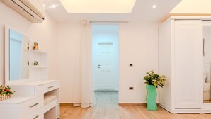 A modern, well-lit room with a white vanity, a mirror, and a teal vase with flowers. - Vesta - Luxury APT - 2BR - Sheikh Zayed I (Sheikh Zayed City)