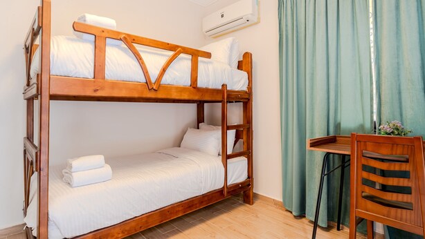 A bunk bed with a wooden frame, white bedding, and a small table with a chair beside it. - Vesta - Luxury APT - 2BR - Sheikh Zayed I (Sheikh Zayed City)