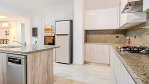 A modern kitchen with a granite countertop, stainless steel appliances, and light wood cabinetry. - Vesta - Luxury APT - 2BR - Sheikh Zayed I (Sheikh Zayed City)