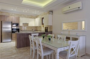 A modern kitchen with a central island, white dining chairs, and a glass table. - Vesta - Luxury APT - 3BR - Sheikh Zayed I (Sheikh Zayed City)