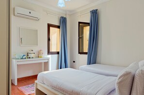 A bedroom with two beds, a desk, a mirror, and an air conditioning unit. - Vesta - Luxury APT - 3BR - Sheikh Zayed I (Sheikh Zayed City)