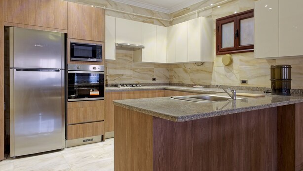 Een moderne keuken met een roestvrijstalen koelkast, twee ovens, een magnetron en een gasfornuis.