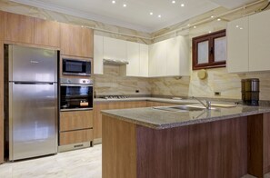 A modern kitchen with a stainless steel refrigerator, double ovens, a microwave, and a gas stove. - Vesta - Luxury APT - 3BR - Sheikh Zayed I (Sheikh Zayed City)