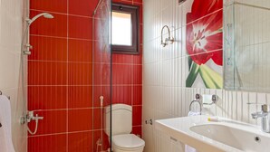 Een badkamer met rode betegelde wanden, een wit toilet, een douche en een wastafel met spiegel.