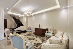 A spacious living room with a grand staircase, elegant furniture, and a chandelier. - Vesta - Luxury Duplex APT - 4BR - Nasr City (Cairo)