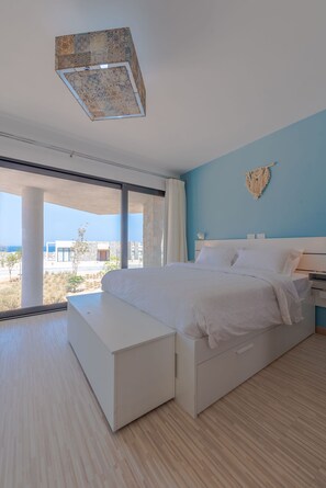 A bedroom with a large bed, a nightstand, and a view of the outdoors. - Vesta - Superior Villa - 2BR - Wadi Jebal IV (Soma Bay)