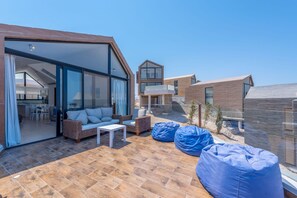 A modern outdoor patio with a dining area, seating, and a view of the adjacent buildings. - Vesta - Superior Villa - 2BR - Wadi Jebal IV (Soma Bay)