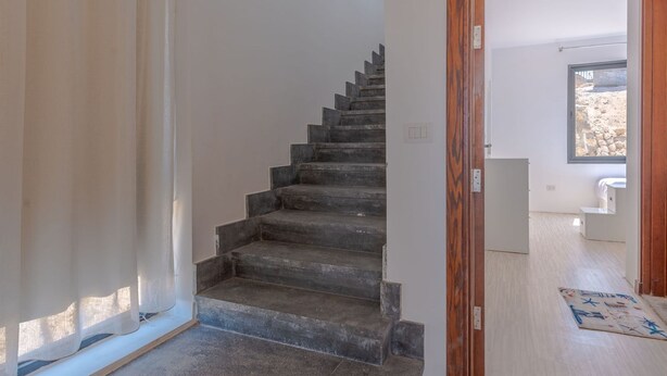 Un escalier menant à un deuxième étage, un cadre de porte en bois et une vue sur une pièce adjacente avec une fenêtre.