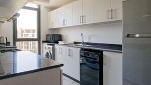 A modern kitchen with white cabinets, a stainless steel refrigerator, a dishwasher, and a microwave. - Vesta - Luxury Apt - 3BR - CFC Xlii (New Cairo)