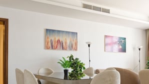 A modern dining area with a round glass table, six chairs, and a potted plant. - Vesta - Luxury Apt - 3BR - CFC Xlii (New Cairo)