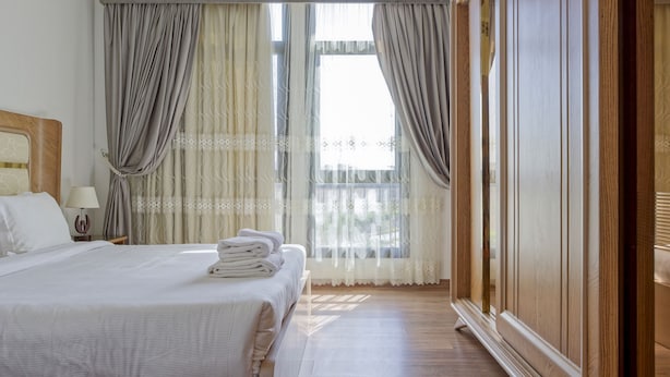 A hotel room with a bed, curtains, a window, and a wooden wardrobe. - Vesta - Luxury Apt - 3BR - CFC Xlii (New Cairo)