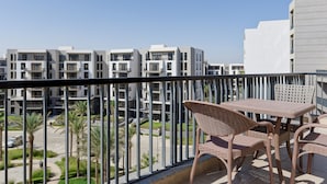 A balcony with wicker furniture and a view of modern apartment buildings. - Vesta - Luxury Apt - 3BR - CFC Xlii (New Cairo)
