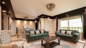A living room with two green sofas, a beige armchair, and a coffee table. - Vesta - Luxury APT - 3BR - Mohandessin II (Giza)