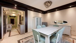 A dining area with a light-colored table and matching chairs, a white cabinet, and a mirror above the counter. - Vesta - Luxury APT - 3BR - Mohandessin II (Giza)