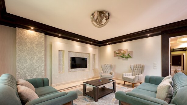 A living room with a large flat-screen TV, two sofas, a coffee table, and a patterned rug. - Vesta - Luxury APT - 3BR - Mohandessin II (Giza)