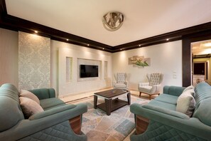A living room with a large flat-screen TV, two sofas, a coffee table, and a patterned rug. - Vesta - Luxury APT - 3BR - Mohandessin II (Giza)