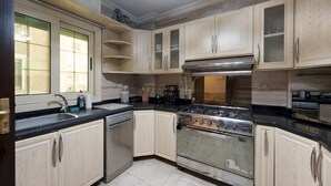 A kitchen with light wooden cabinets, a stainless steel stove, and a dishwasher. - Vesta - Luxury APT - 3BR - Mohandessin II (Giza)