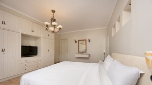 A bedroom with a large bed, white cabinetry, a television, and a chandelier. - Vesta- Luxury Panoramic Duplex - 3br- Zamalek II (Cairo)