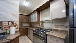 A modern kitchen with a gas stove, oven, and stainless steel refrigerator. - Vesta- Luxury Panoramic Duplex - 3br- Zamalek II (Cairo)
