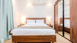 Une chambre à coucher avec un lit en bois, des lampes de chevet, un grand miroir et un appareil de climatisation.