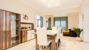 Un salon moderne avec un coin repas, comprenant un meuble en bois, une table à plateau en verre et un canapé.
