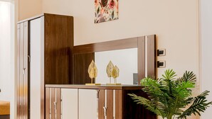 Une armoire en bois avec des portes miroir, une plante et un miroir décoratif placé au-dessus.