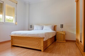 Um quarto com uma cama de madeira, uma mesa de cabeceira e uma janela com persianas.