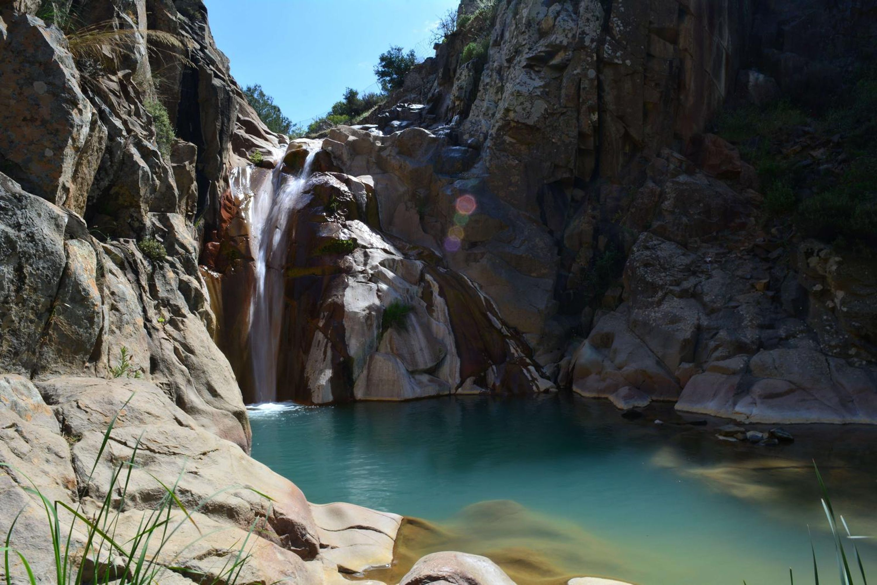 Paisaje natural con una cascada y una poza cristalina.