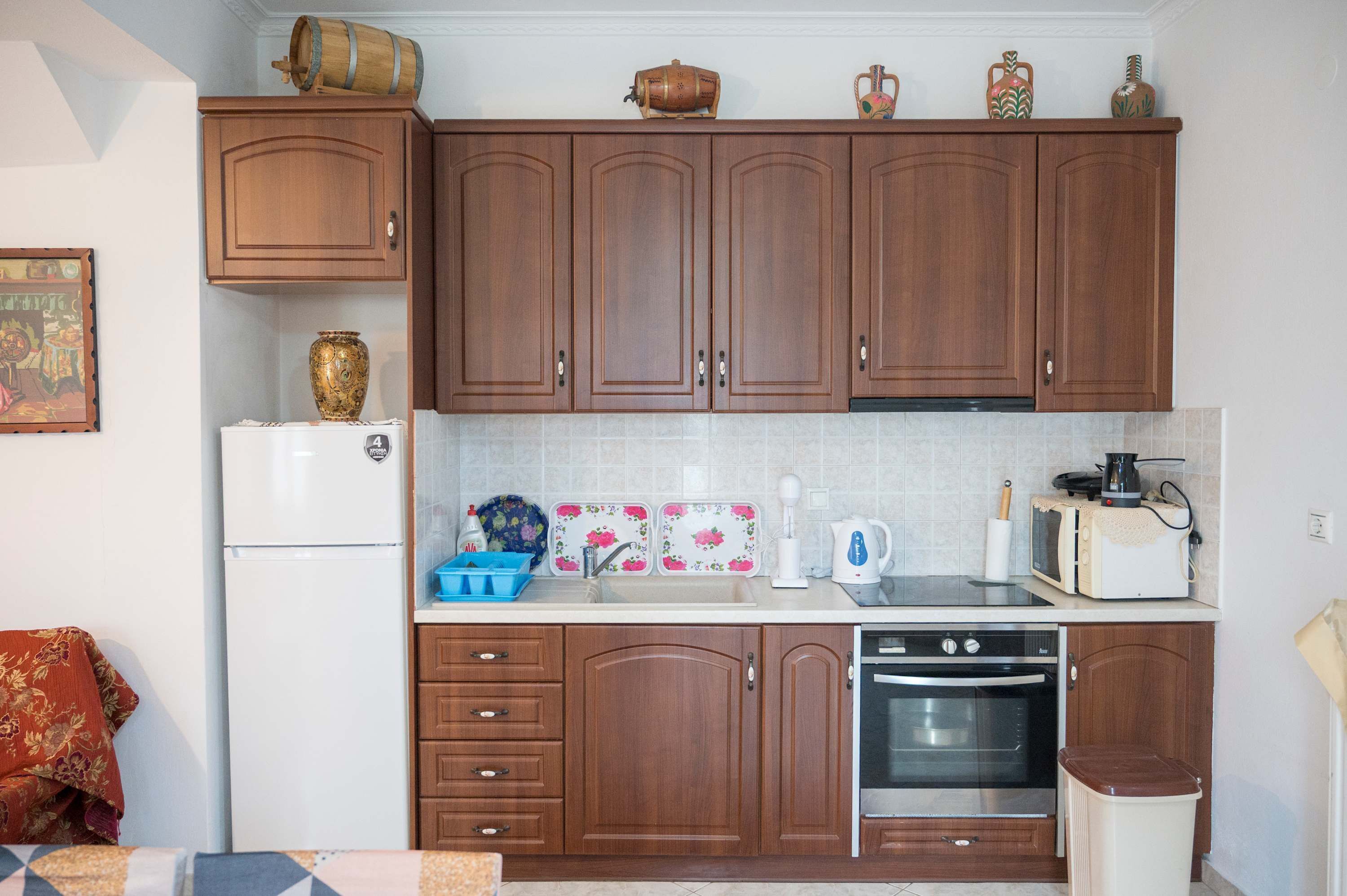 Una cocina compacta con armarios de madera, un refrigerador blanco, un microondas, un tostador y una estufa.