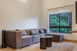 A modern living room with a grey sectional sofa, a round coffee table, and a standing heater. - NOK Peaceful 3BR in Medellin (Medellín)