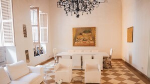 Un espace repas comprenant une longue table et des chaises, un canapé blanc et un lustre.