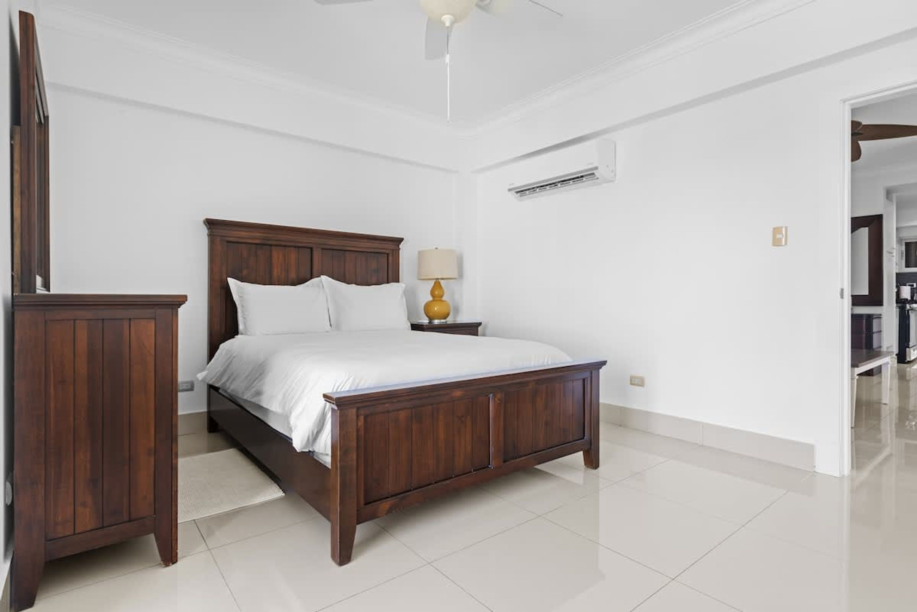 Un dormitorio con una cama de madera, una mesita de noche con lámpara y un armario.