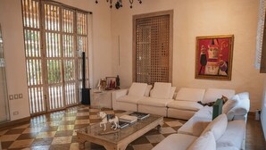 Uma sala de estar espaçosa com um sofá branco, uma mesa de centro com livros e uma janela grande com vista para o verde.