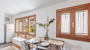 A dining area with a table, chairs, a vase with flowers, and a view through the window. - Beautiful Home in the Heart of Mallorca with Air Conditioning and Wi-Fi (Petra)