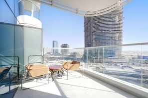 A balcony with wicker chairs and a small table, overlooking a cityscape with modern buildings. - Stayshort - Sleek and Modern Studio in Arjan That Sleeps 2 (Dubai)