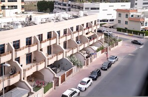 Ein mehrstöckiges Wohnhaus mit Balkonen, einem Parkplatz und Blick auf die Straße.