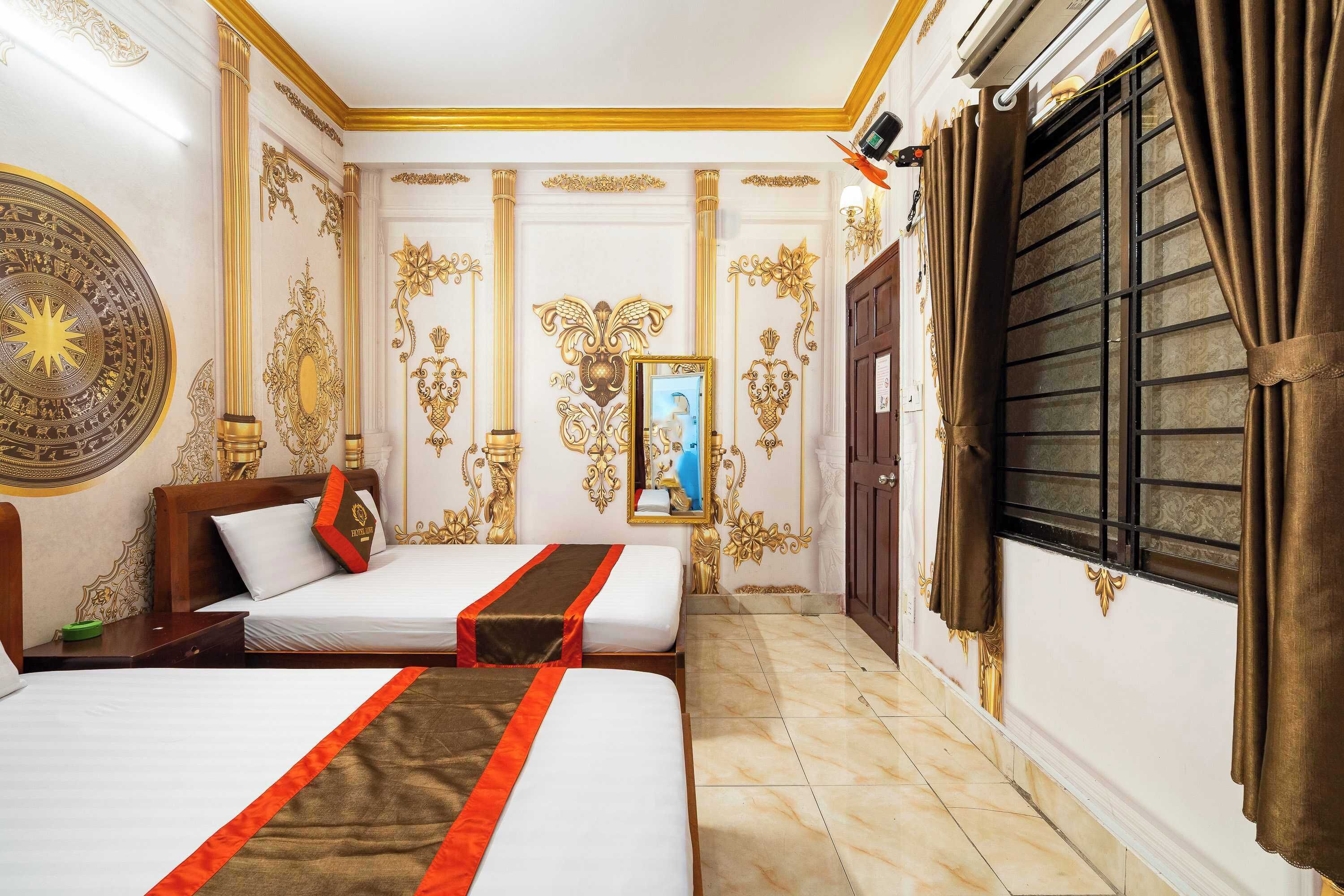 A hotel room with two beds, ornate wall decorations, a large mirror, and a window with curtains.