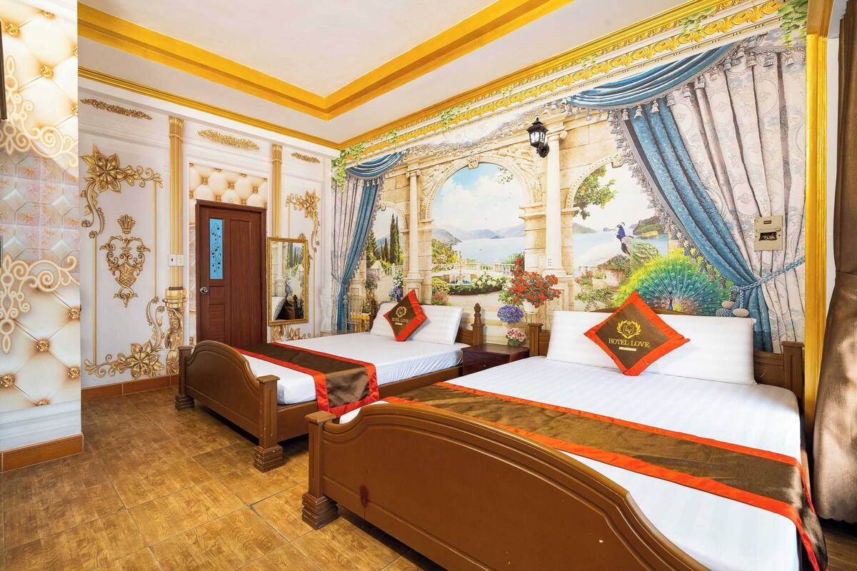 A hotel room with two beds, a large window with curtains, and a mural of a landscape.