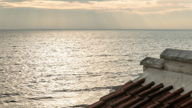 Une vue sur la mer depuis une structure en béton dotée d’une rambarde métallique.