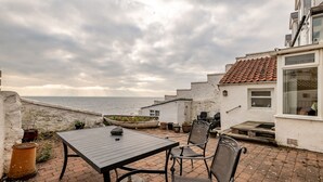 An outdoor patio with a table and chairs, overlooking the sea. - Appleton House | Lower Largo (Lower Largo)