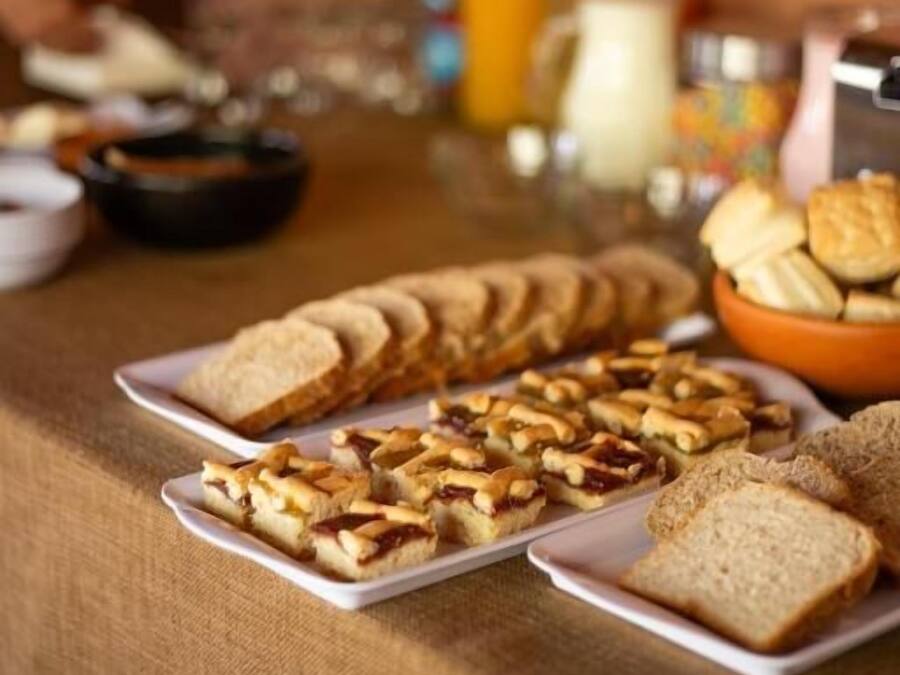 A buffet table with sliced bread, pastries, and a pitcher of orange juice.