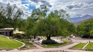 A landscaped garden with pathways, a central fountain, and a building with a sloped roof. - Don Juan posada andina (Tilcara)