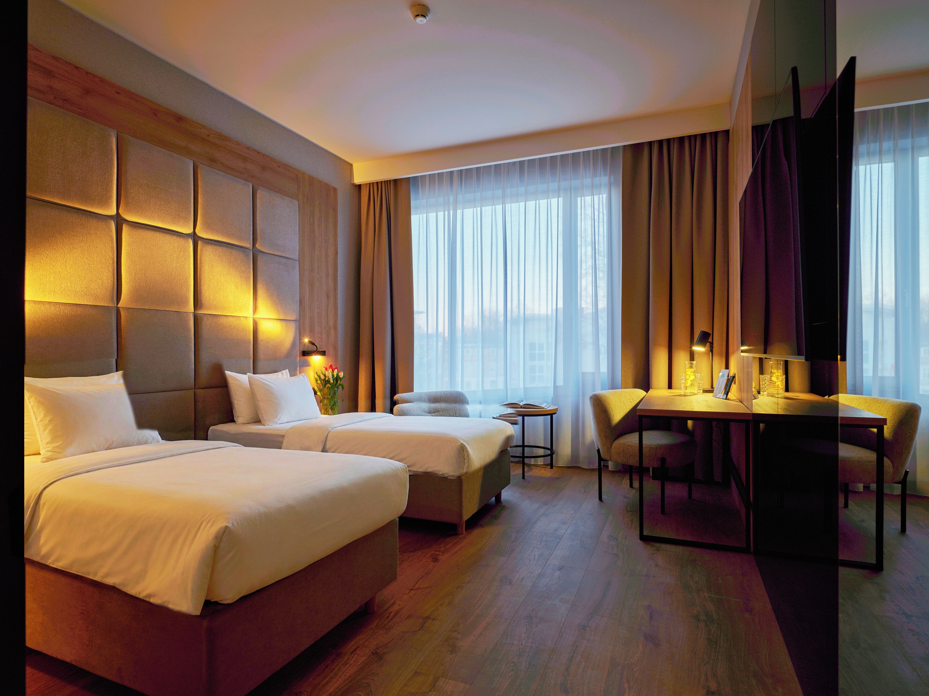 Ein Hotelzimmer mit zwei Betten, einem Schreibtisch und einem Stuhl.