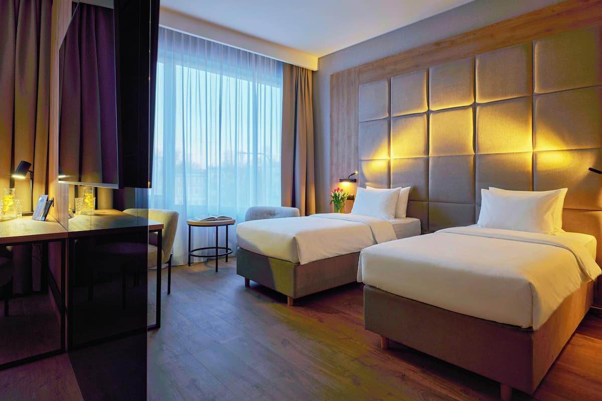 A hotel room with two beds, a desk, and a chair.