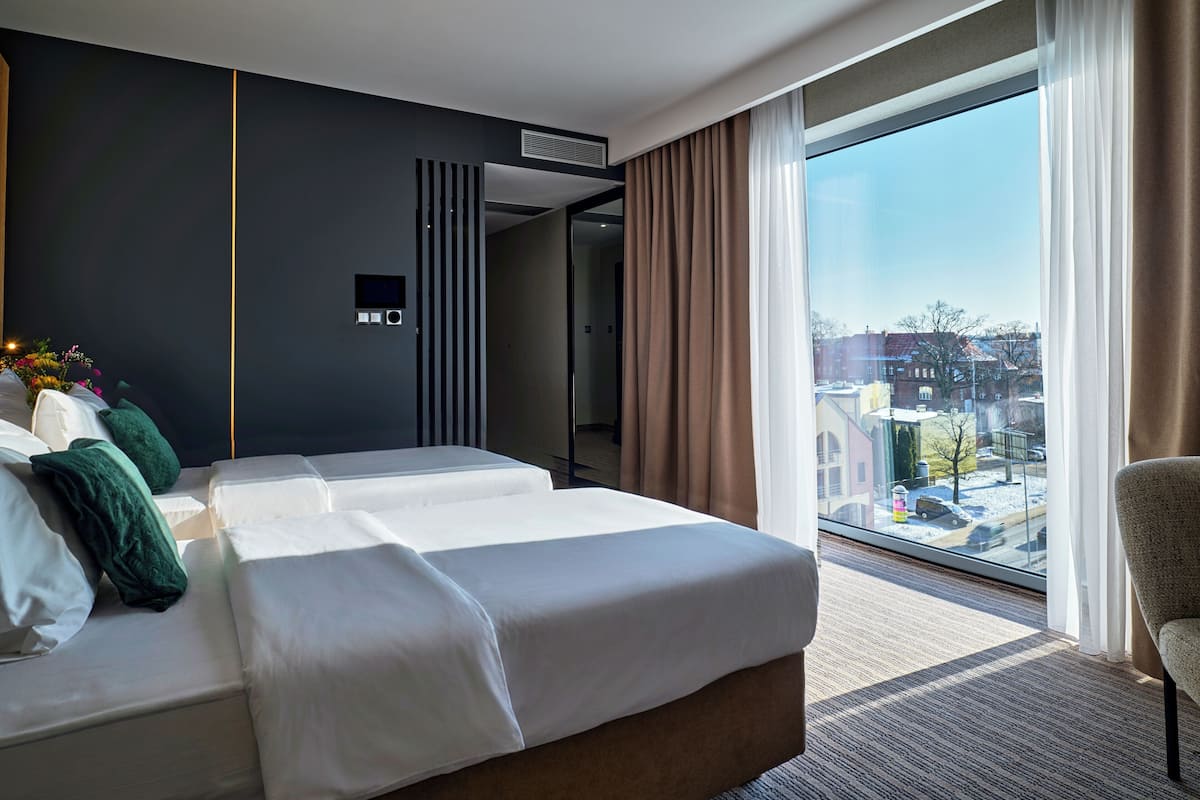 A modern hotel room with a large bed, a seating area, and a view of the city.