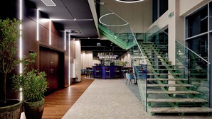 A modern interior with a bar area, a staircase, and potted plants.