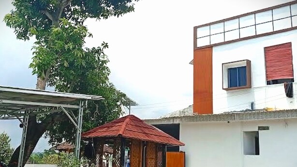A residential area with a white building, a red-roofed structure, and a parked motorcycle. - OYO 95038 Khanza Stay (Semarang)