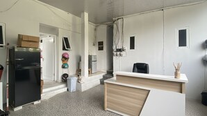 A modern office space with a reception desk, a black refrigerator, and a white wall with electrical outlets. - OYO 95038 Khanza Stay (Semarang)